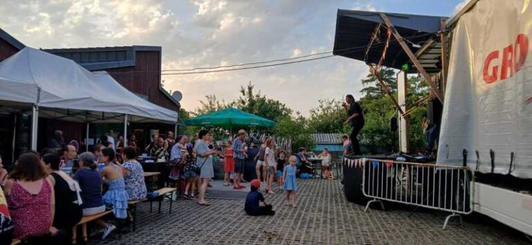 Fête de la Musique à Andouillé-Neuville, scène musicale installée sur un camion en plein air avec des spectateurs attablés qui mangent dehors