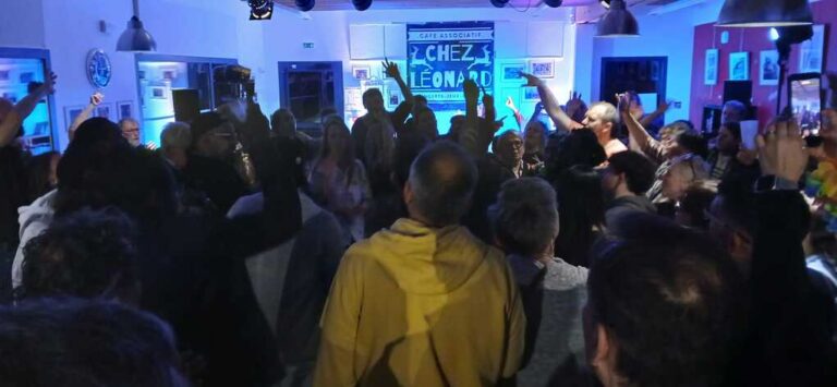 Audience regardant une performance sur scène éclairée en bleu chez Chez Léonard